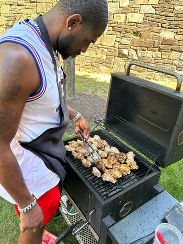 Man grilling chicken on an outdoor barbecue grill.