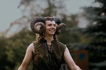 A candid photo from the waist up of a stilt performer dressed as a faun