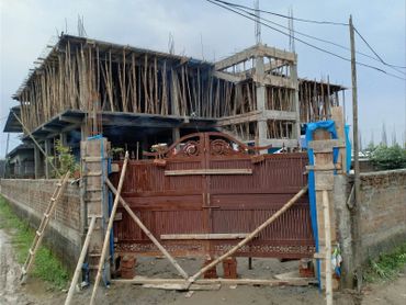 Building under construction with bamboo scaffolding and a wooden gate.