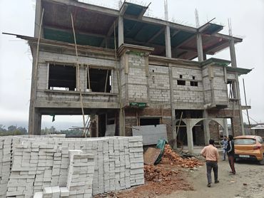 Unfinished building with construction materials and workers outside.