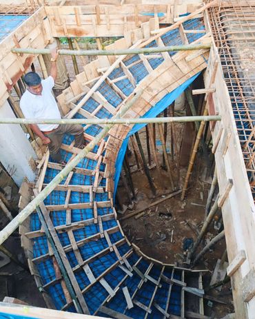 Man inspecting a curved wooden and metal staircase framework under construction.