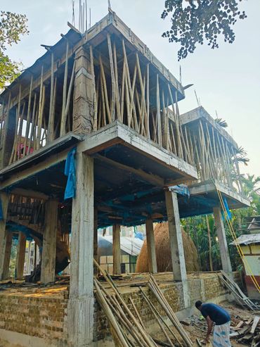 Under-construction building supported by bamboo scaffolding with a worker nearby.