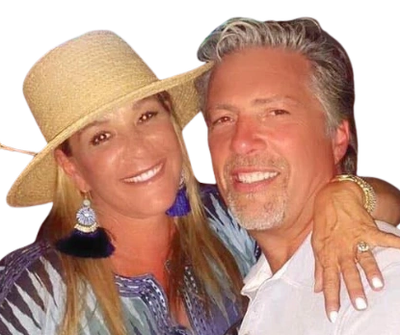 A smiling couple posing closely together, the woman wearing a straw hat and tassel earrings.