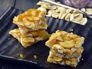 Crunchy peanut brittle squares on a black plate.
