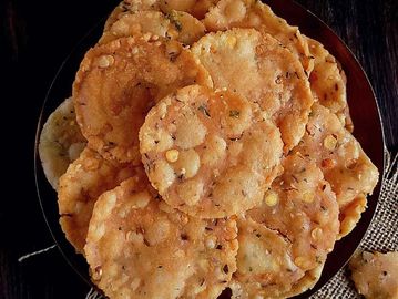 A plate of crispy, round lentil snacks with seasoning.