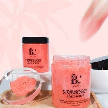 Strawberry body scrub jars on display with a soft pink background.