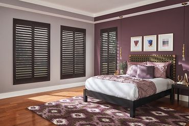 A stylish bedroom with purple walls and wooden shutters.