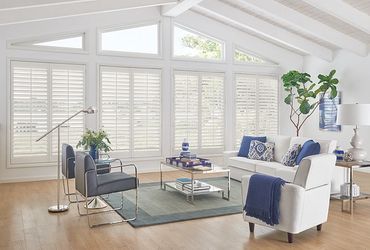 Bright living room with white and blue furniture and large windows.