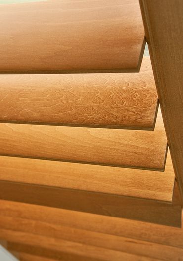Close-up of wooden window blinds with warm light.