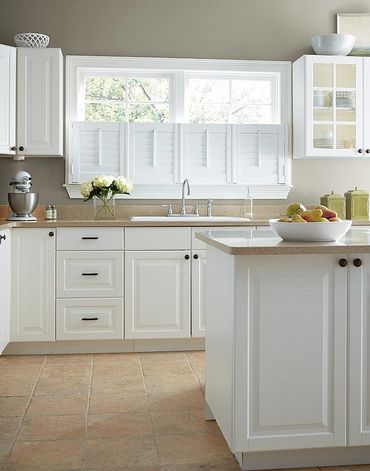 Bright white kitchen with beige countertops and tiled floor.