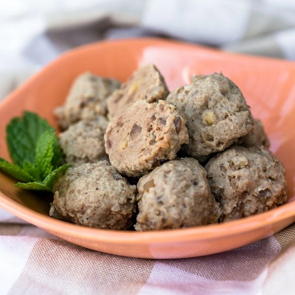 A bowl of homemade meatballs garnished with mint leaves.