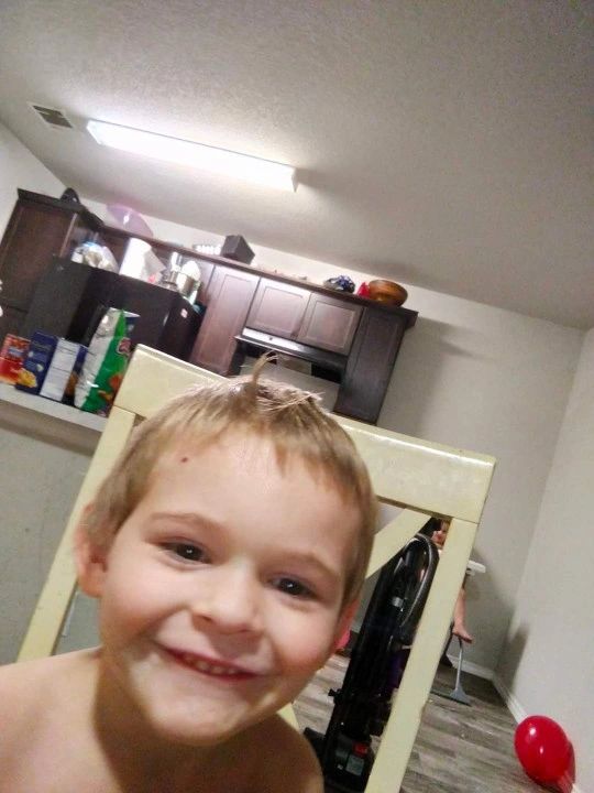 A smiling young boy with a messy face in a kitchen setting.