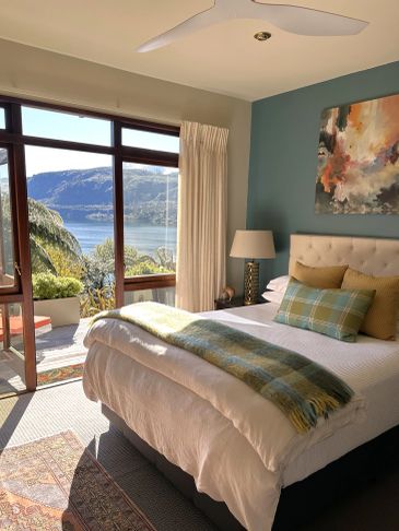 Cozy bedroom with lake view and open patio door.
