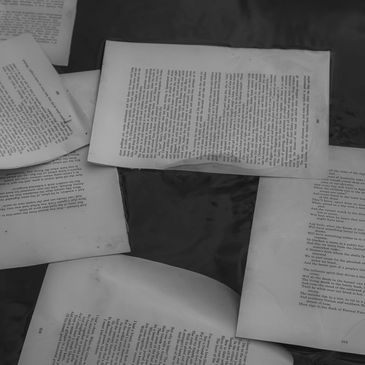 Black and white image of book pages floating on water.