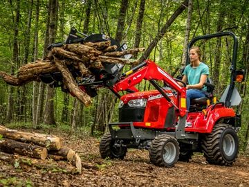 A woman operating a red tractor lifting logs in a forest.