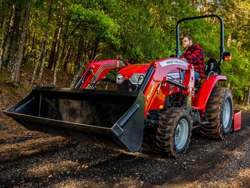 A man drives a red Massey Ferguson tractor on a forest path.