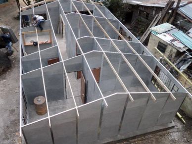 Concrete block structure with wooden framework for roof support under construction.