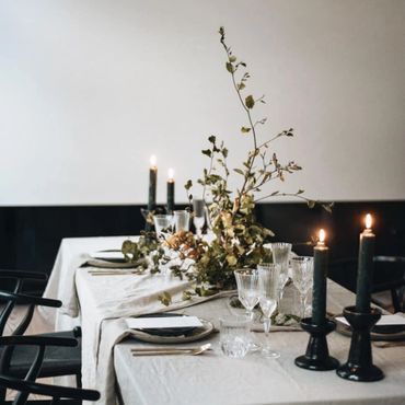 Elegant dining table with candles and greenery centerpiece.