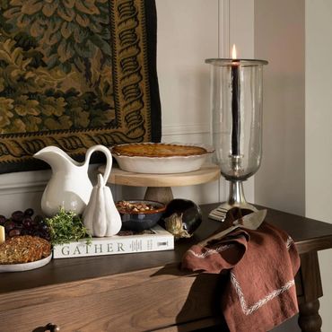 A cozy autumn table setup with a pie, candle, and rustic decorations.