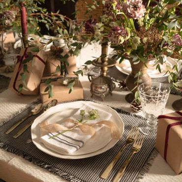 Elegant table setting with candles, flowers, and wrapped gifts for a special occasion.