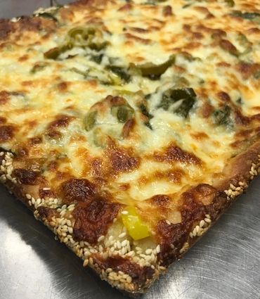 Rectangular pizza with sesame seeds on the crust, and like a traditional pizza, cheese is on top