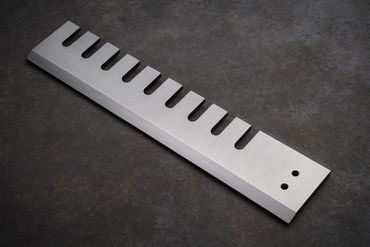 A sleek metal comb with wide teeth on a dark surface.