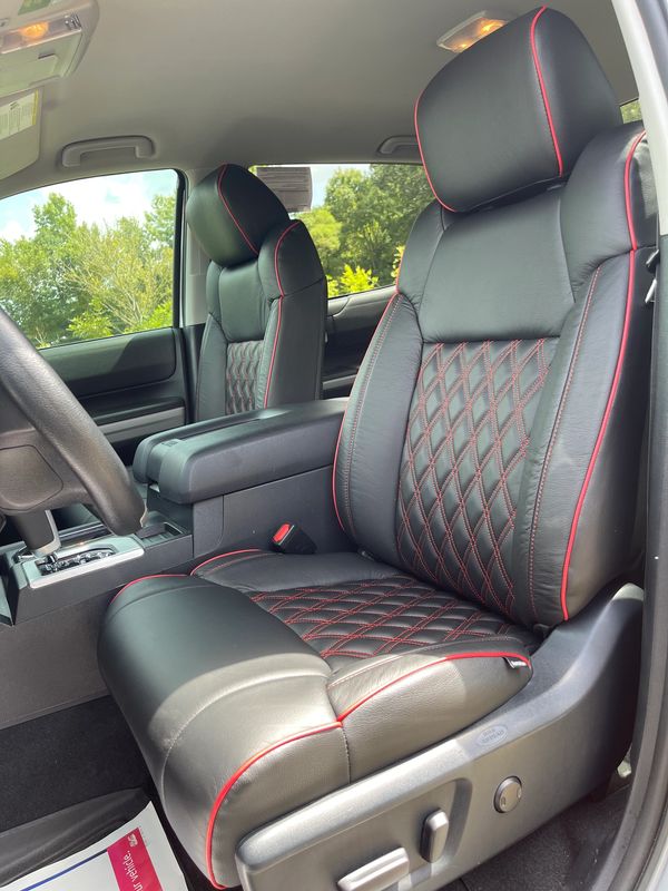Luxurious black leather car seats with red stitching and piping detail.