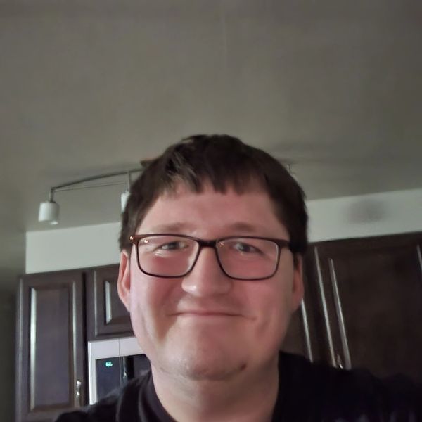 Smiling man with glasses in a kitchen setting.