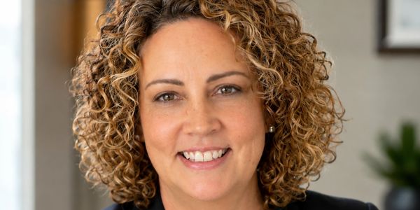 Smiling woman with curly hair in a professional setting.