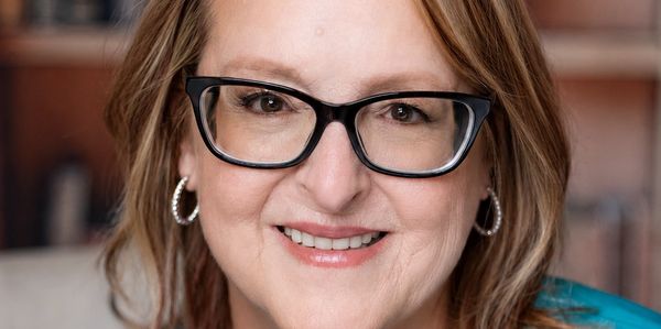 Smiling woman with glasses and hoop earrings.