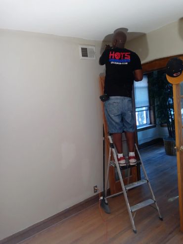 “Handymen on the Spot professional completing an interior painting project, carefully painting alon