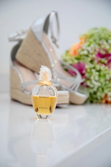 Givenchy Amarige perfume with shoes and flowers in background.