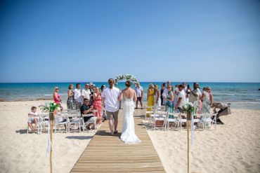 Beach wedding ceremony with guests and ocean backdrop.