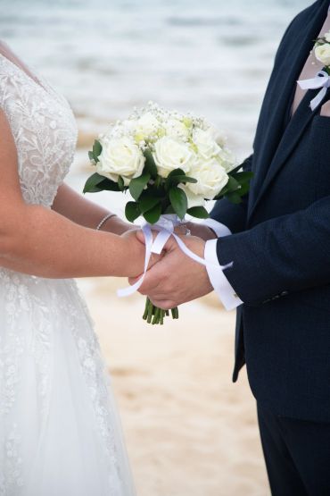 Bride and groom holding hands with a bouquet.