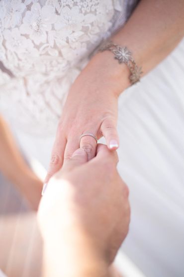 Close-up of a hand with a ring and delicate lace fabric in the background.