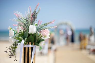 Close-up of floral wedding decorations on a beach.