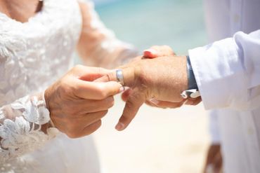 A bride putting a wedding ring on a groom's finger.