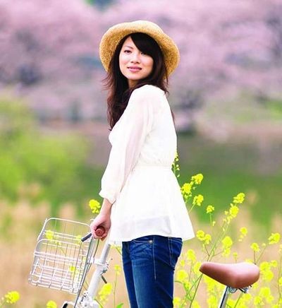 GIRL in happy state with bicycle in flower garden