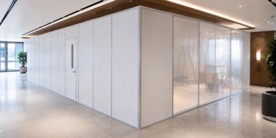 Modern office space with white partition walls and glass panels.