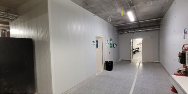 Empty industrial hallway with doors and safety signs.