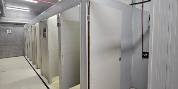 Row of open shower stalls in a clean bathroom.
