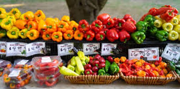 Colorful bell peppers and other vegetables displayed at a market stand.