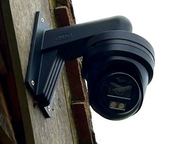 Black security camera mounted on an outdoor wall.