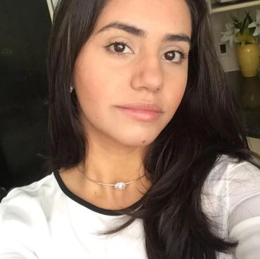 Close-up of a young woman with long dark hair and a delicate necklace.