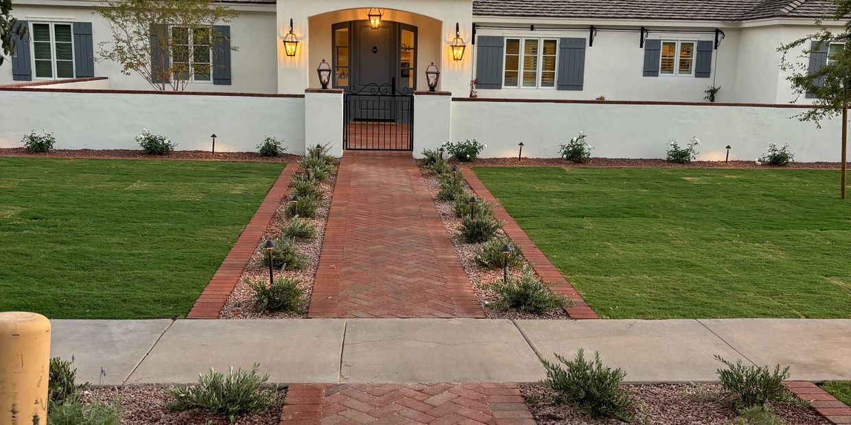 A charming house with a red brick pathway and well-maintained lawn.