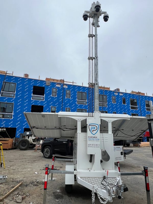 Mobile surveillance unit with solar panels at a construction site.