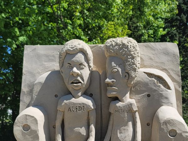 Sand sculpture of two characters sitting on a couch.