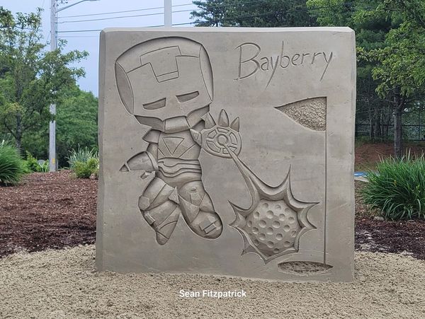 Sand sculpture of Iron Man playing golf with the word 'Bayberry'.