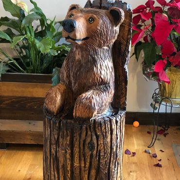Wooden bear sculpture carved from a log, sitting upright.