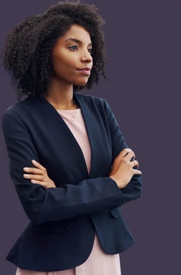 Confident woman with arms crossed, wearing a navy blazer and light pink top.